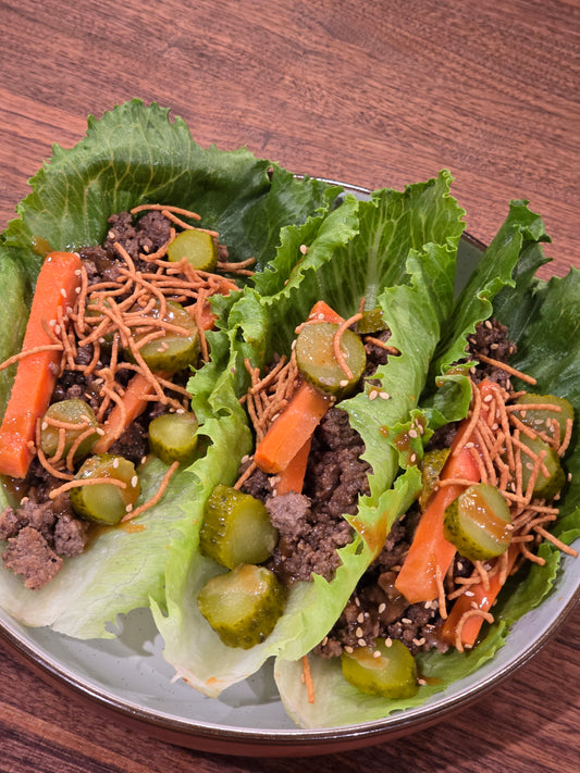 “Ground beef lettuce wraps with pickled carrots, chopped pickles, crunchy noodles, and sesame seeds served in fresh lettuce boats.”